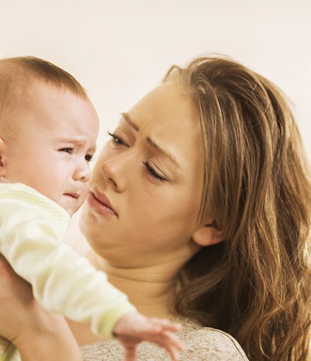 Mother and crying baby boy. Young mother holding her baby boy who is crying.